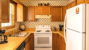 Una cocina con armarios de madera, estufa, fregadero y refrigerador.
