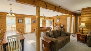 Un interior de madera con una mesa de comedor, sillas, un sofá y una lámpara.