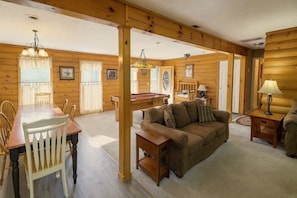 A wooden interior with a dining table, chairs, a sofa, and a lamp. - Hoot N Holler 5 Bedroom Chalet (Pigeon Forge)