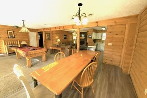 Un interior de madera con mesa de billar, una mesa de comedor y sillas.