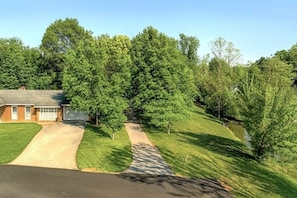 A residential property with a driveway, lawn, and trees. - Hoot N Holler 5 Bedroom Chalet (Pigeon Forge)