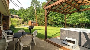 Un patio con una parrilla, mobiliario exterior y un jacuzzi.