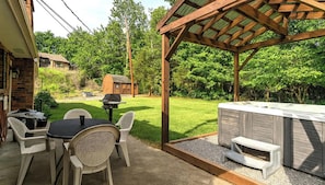 A patio with a grill, outdoor seating, and a hot tub. - Hoot N Holler 5 Bedroom Chalet (Pigeon Forge)