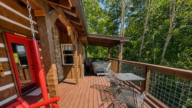 Eine Holzterrasse mit Schaukelstuhl, Tisch und Whirlpool.