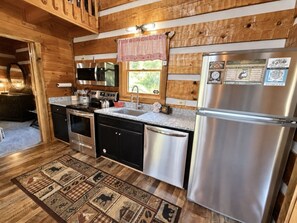 A compact kitchen with a stainless steel refrigerator, a microwave, a stove, and a dishwasher. - Blu's Blessed View 1 Bedroom Cabin (Sevierville)
