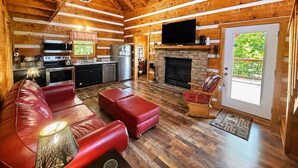 Ein Holzblockhaus-Interieur mit Küche, Wohnzimmer, Kamin und Fernseher.
