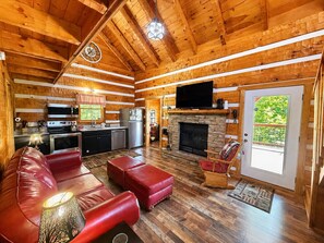 A log cabin interior with a kitchen, living room, fireplace, and a television. - Blu's Blessed View 1 Bedroom Cabin (Sevierville)