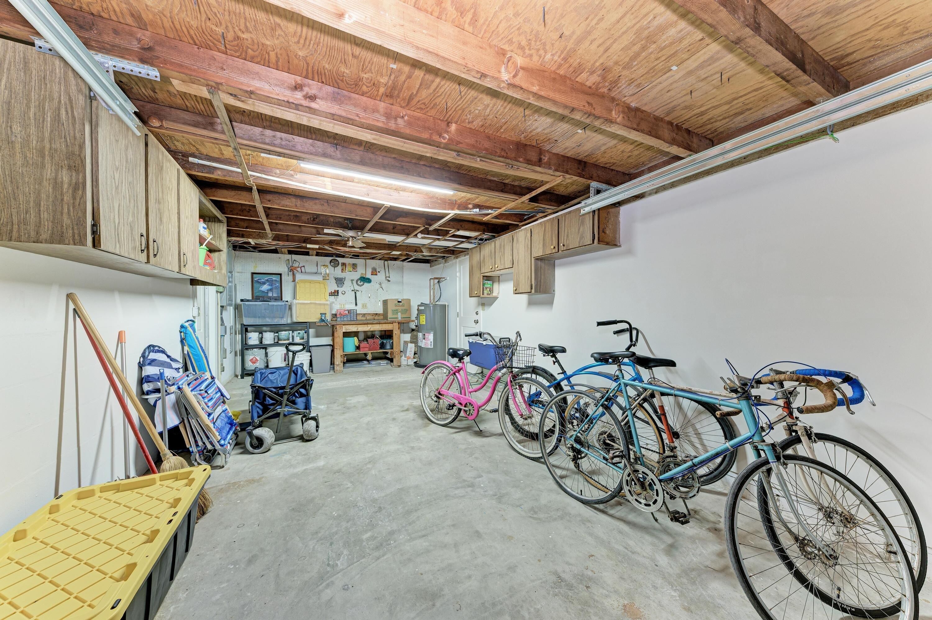 A room with a concrete floor, wooden ceiling beams, and bicycles.