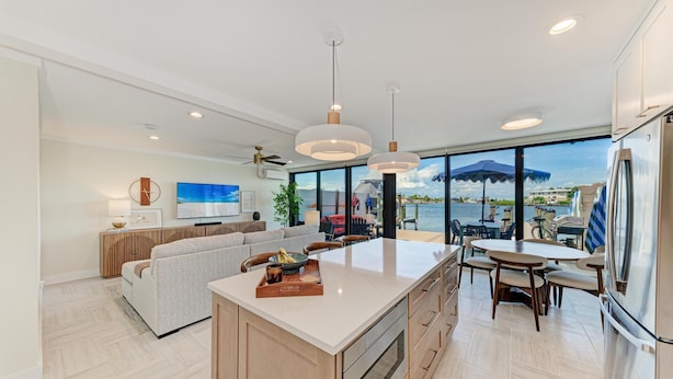 Una cocina moderna con una isla grande, comedor y vistas al mar.