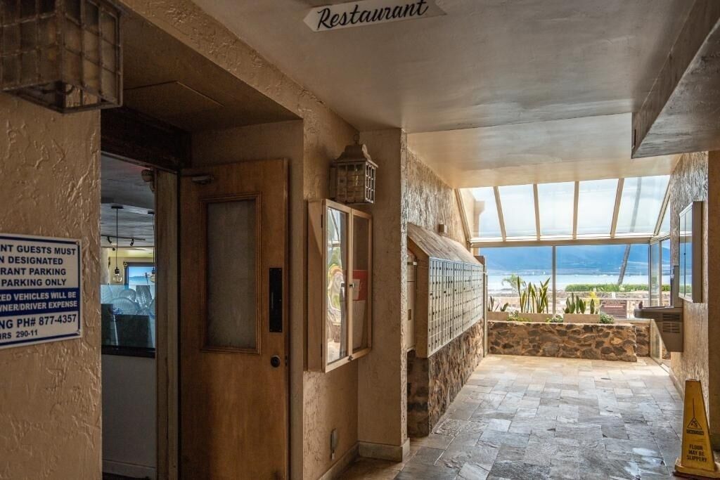 Restaurante com vista para o oceano, uma parede de pedra e placa indicando estacionamento reservado.