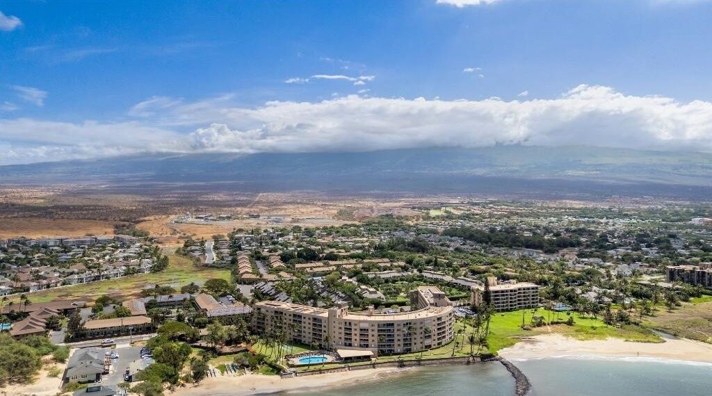 Un resort costero con varias construcciones, una playa y vista del paisaje lejano.