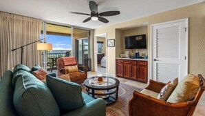 A living room with a sofa, armchairs, a coffee table, and a ceiling fan. - Menehune Shores, #507 2 Bedroom Condo (Kihei)