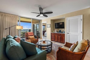 Ein Wohnzimmer mit einer Couch, Sesseln, einem Couchtisch und einem Deckenventilator.