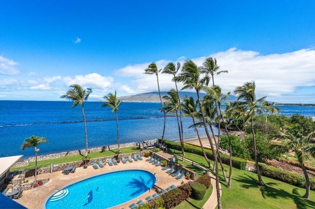 A resort pool with a view of the ocean and a mountain in the background.