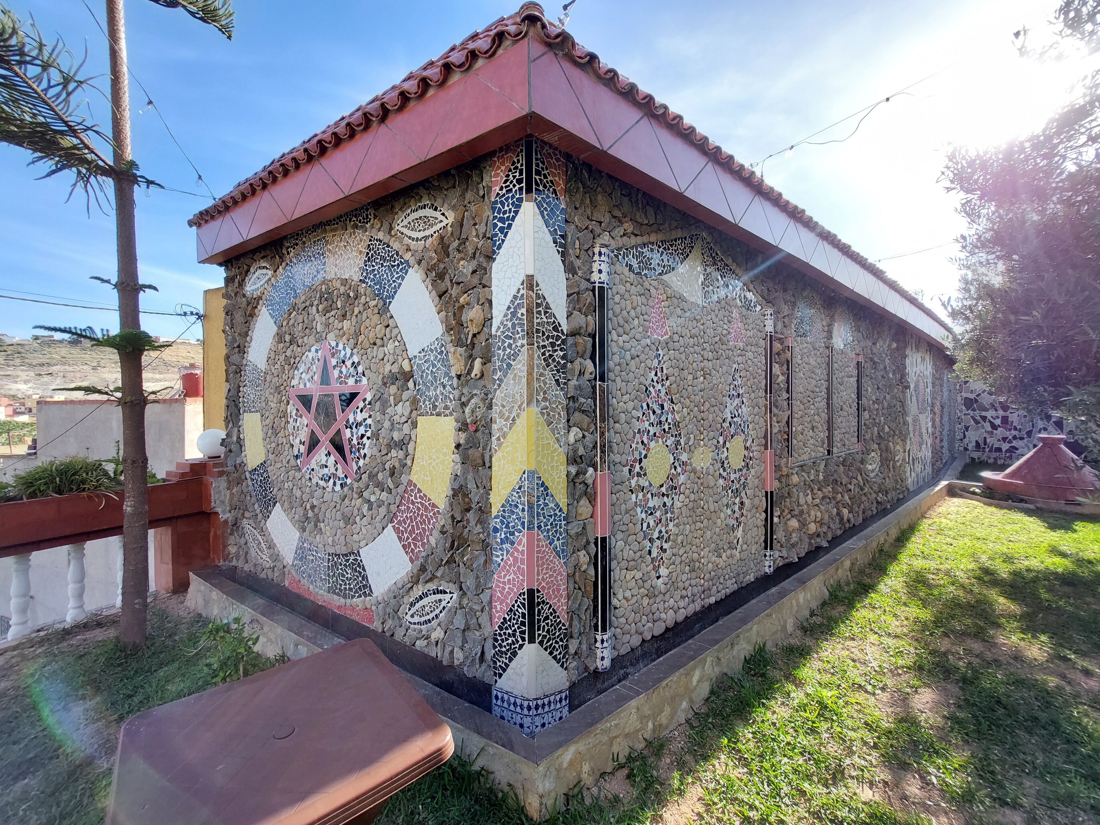 A building with a tiled exterior, a red roof, and a stone base.