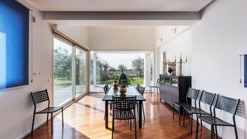 Un espace repas moderne avec un plancher en bois, une table entourée de chaises et une vue sur l’extérieur.