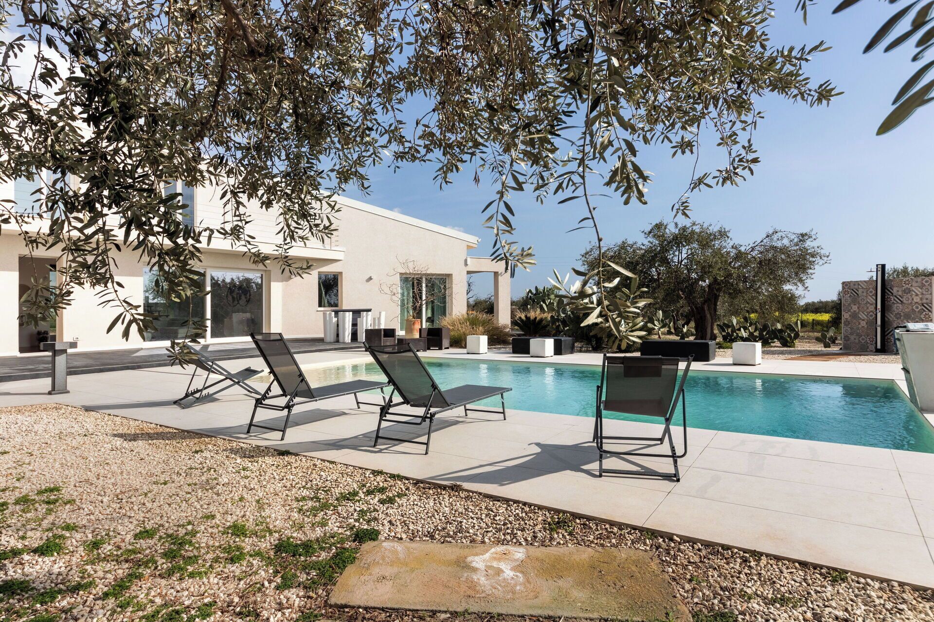 A modern pool area with lounge chairs, a swimming pool, and a building with large windows.