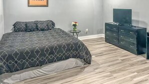 Ein Schlafzimmer mit einem Bett, einer Kommode, einem Fernseher und einem kleinen Tisch mit Blumen.