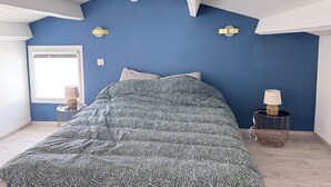 Ein Schlafzimmer mit einem Bett, zwei Wandlampen, einem Fenster und einer Tür.