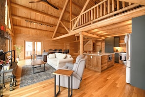 Ein geräumiges Blockhaus-Interieur mit Wohnbereich, Küche und einer Treppe.