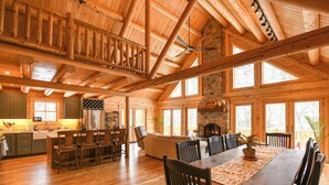 Un intérieur spacieux de chalet en bois, comprenant un coin repas, une cuisine et un salon.