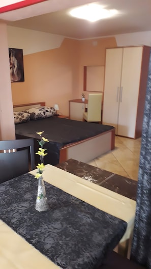 Ein kleines, gemütliches Zimmer mit Bett, Schreibtisch, Stuhl, Schrank und einem Bild an der Wand.