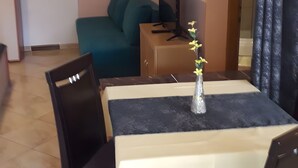 A dining area with a table, chairs, a vase with flowers, a sofa, a TV, and a wall-mounted air conditioner. - Apartment 'Vivien' with Sea View, Wi-Fi and Air Conditioning (Kustići)