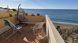 A terrace with a view of the sea, featuring a hanging chair, a lounge chair, and potted plants. - 011 / GRAND T3 RESIDENCE LE FRANCE (Sète)