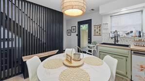 Een moderne keuken met een spoelbak, een eethoek met een ronde tafel, en een trap met een zwarte leuning.