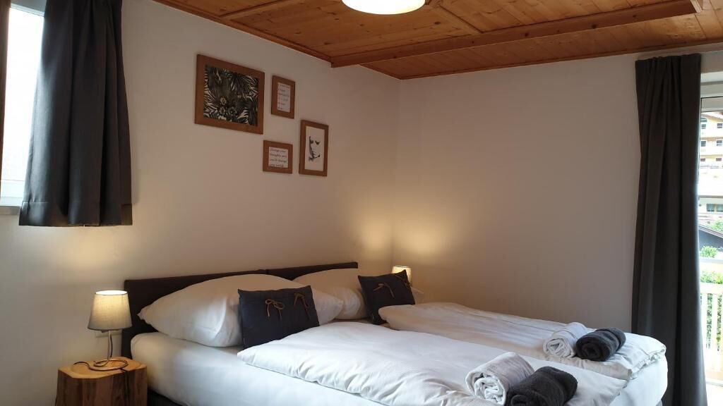 Ein Schlafzimmer mit Bett, Kissen, einem Nachttisch und gerahmten Bildern an der Wand.