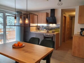 Eine moderne Küche mit Holzausstattung, einem Einbauherd und einem Essbereich mit Tisch und Stühlen.