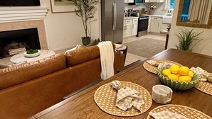 Een moderne woonkamer met een houten eettafel, een bank, een televisie en een plafondventilator.