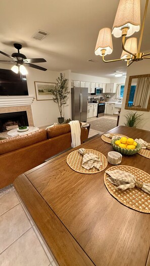 Een moderne woonkamer met een houten eettafel, een bank, een televisie en een plafondventilator.
