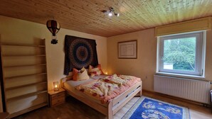 Een slaapkamer met een bed, een raam, een wandtapijt en een radiator.
