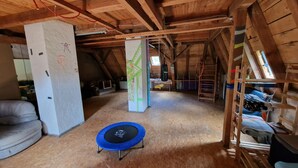 Una habitación estilo loft con trampolín, vigas de madera y cama en un entrepiso.