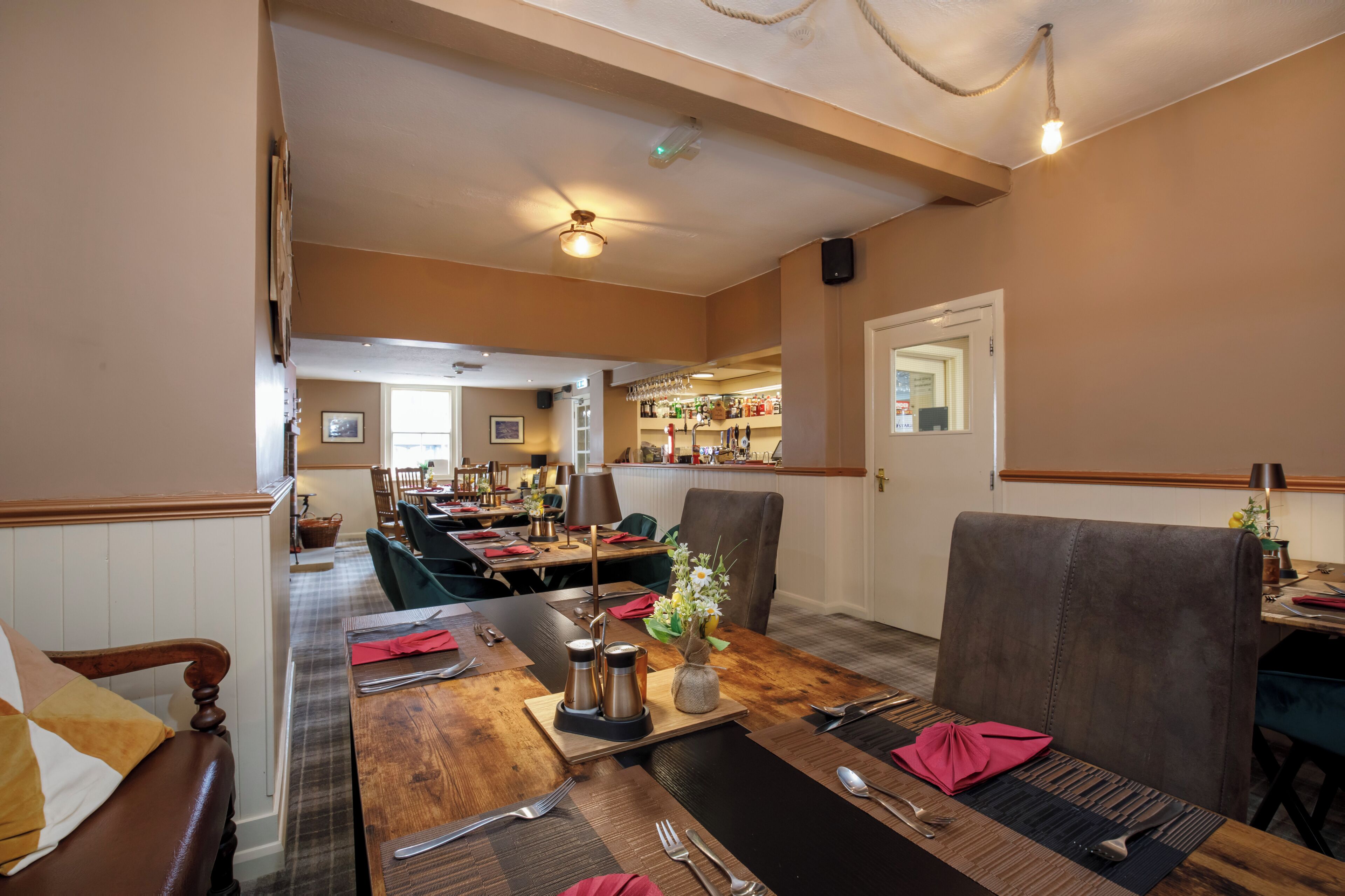 A restaurant with wooden tables, chairs, and a bar area.