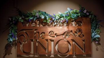 Un letrero de bienvenida con la inscripción 'Welcome to The Union' en letras grandes, rodeado de follaje decorativo.