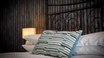 A bed with a striped pillow, a plain pillow, and a metal headboard.