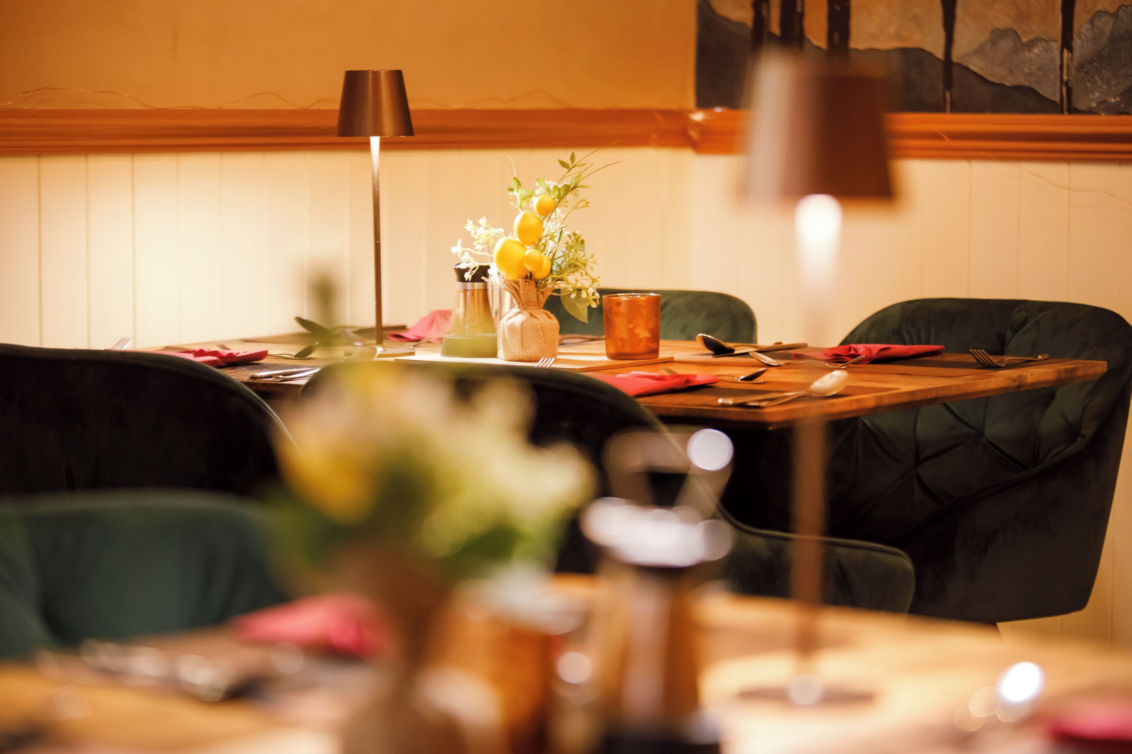 Una mesa de comedor con sillas, un florero con flores, una vela y una lámpara.