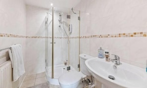 Une salle de bain avec une douche à parois de verre, des toilettes et un lavabo avec un miroir.
