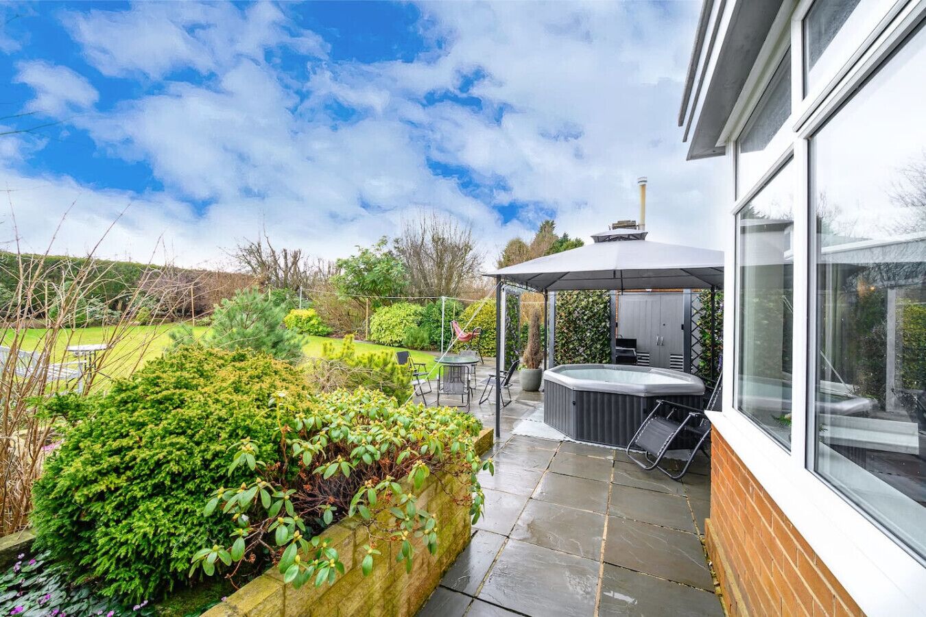 A modern house with a patio, a hot tub, and a garden.. CH-Stylish Home with Hot Tub & Garden