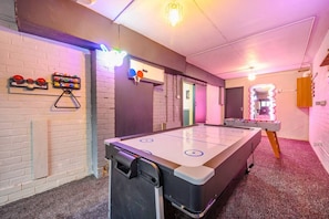 Ein Zimmer mit Shuffleboard-Tisch, Kicker und Wand-Pingpong.