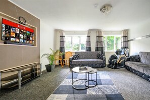 Ett modernt vardagsrum med en vägg avsedd för Netflix, en soffa, ett soffbord och en spelstol.