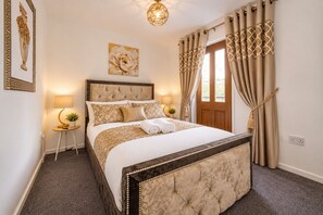 Een hotelkamer met een groot bed, een bedlampje, een decoratief wandobject en gordijnen met een giraffeprint.