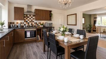 A modern kitchen with wooden cabinets, a dining area with a table set for six, and a chandelier.