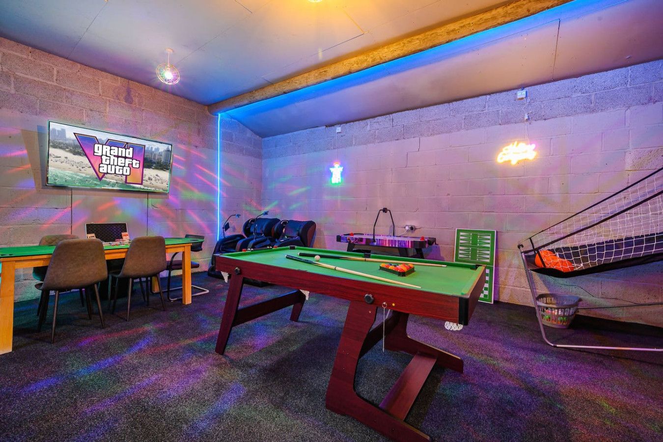 Uma mesa de bilhar com cadeiras, uma mesa de sinuca e um letreiro neon.