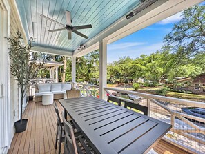 Eine überdachte Terrasse mit Deckenventilator, einem Esstisch und einer Sitzecke.