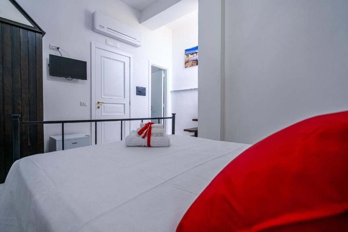Una habitación de hotel con cama, televisión, aire acondicionado y puerta.