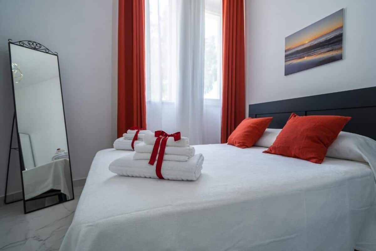 Habitación de hotel con una cama, un espejo grande y un cuadro en la pared.