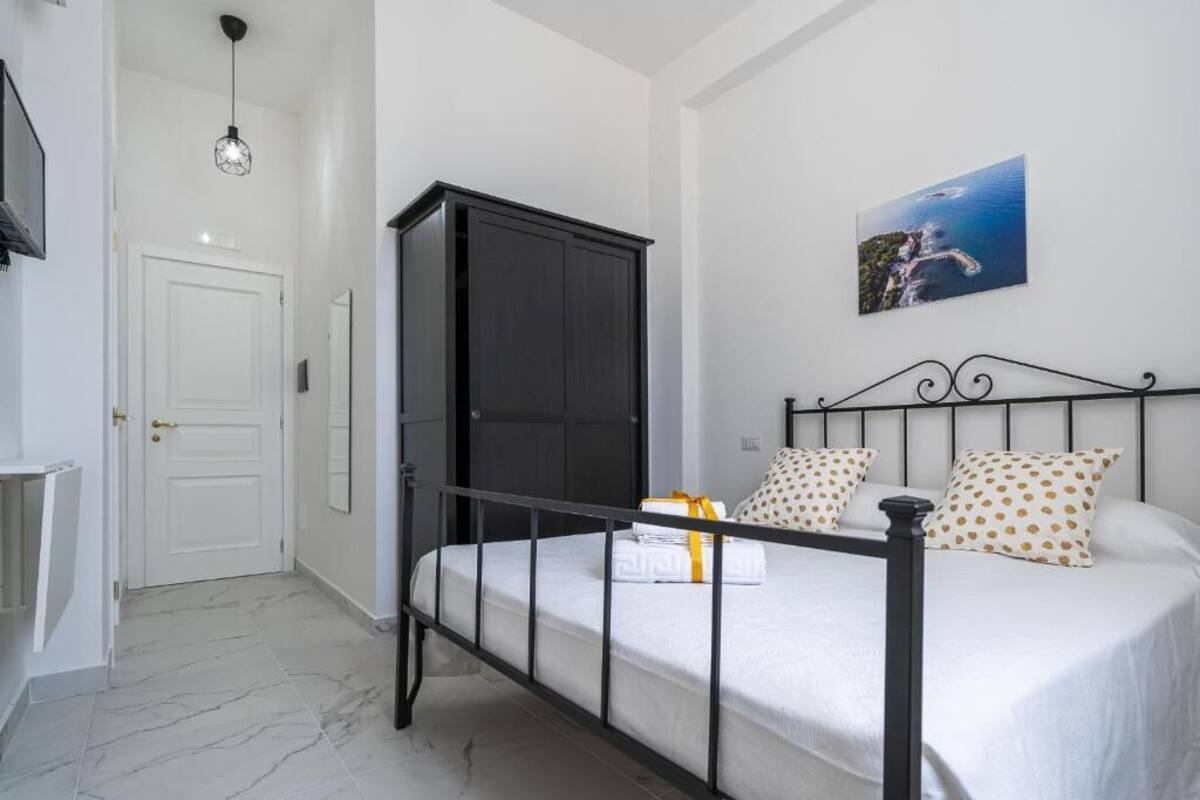 Un dormitorio con cama, armario, puerta y un cuadro colgado en la pared.
